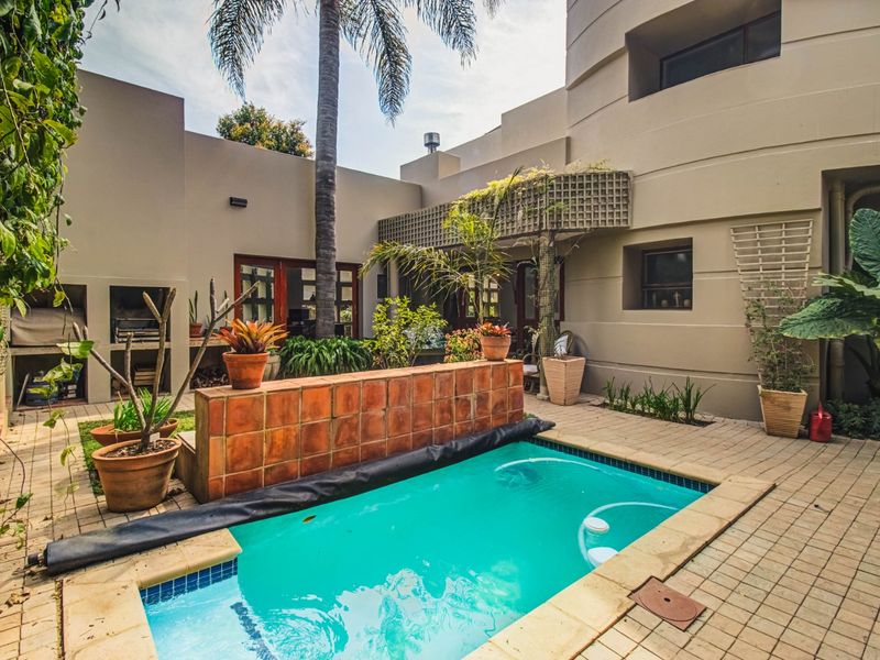 A private courtyard featuring a swimming pool, paved patio area, and a built-in braai, perfect for outdoor entertaining.