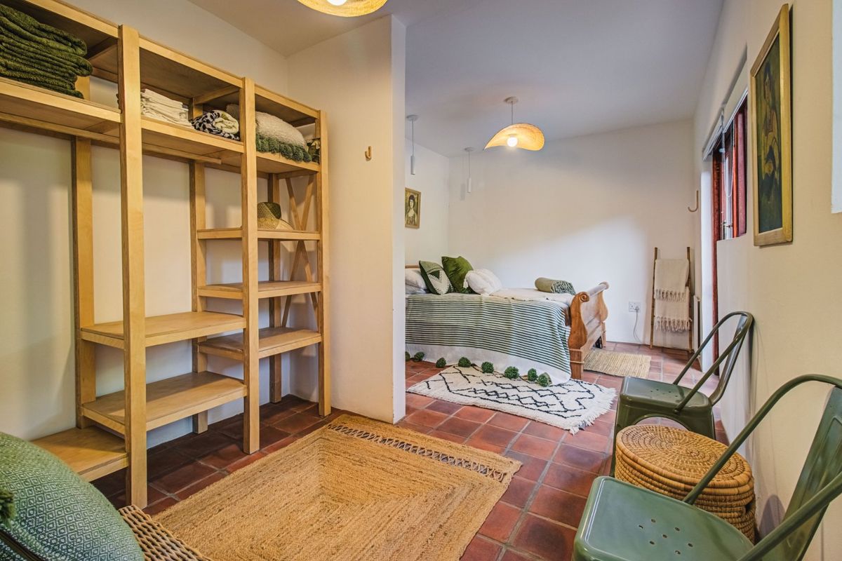 A bedroom featuring terracotta tile flooring and a functional layout with a partitioned storage area and direct access to the outdoors via a sliding door.
