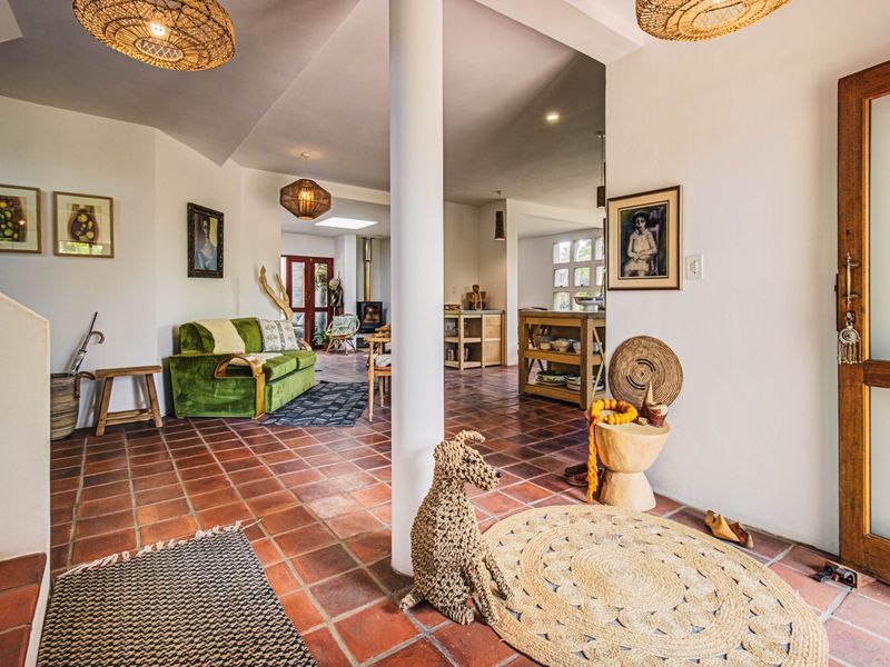 Spacious open-plan living area featuring terracotta floor tiles, a central structural column, and a cozy wood-burning stove, creating a warm and inviting atmosphere.