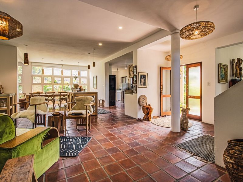 Spacious open-plan living and dining area featuring classic terracotta floor tiles, abundant natural light, and seamless flow to the exterior through timber-framed glass doors.
