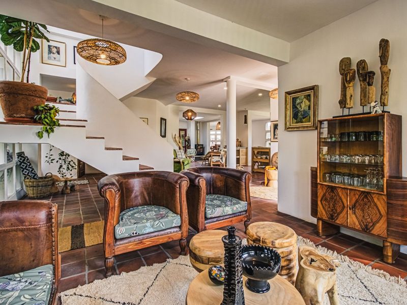 Spacious open-plan living area featuring terracotta floor tiles, a prominent staircase, and a seamless flow into the adjacent dining and kitchen spaces.
