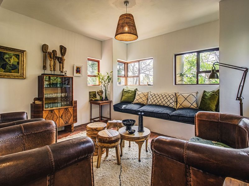 A cozy living room featuring a built-in window seat, terracotta tile flooring, and large casement windows that provide natural light and garden views.