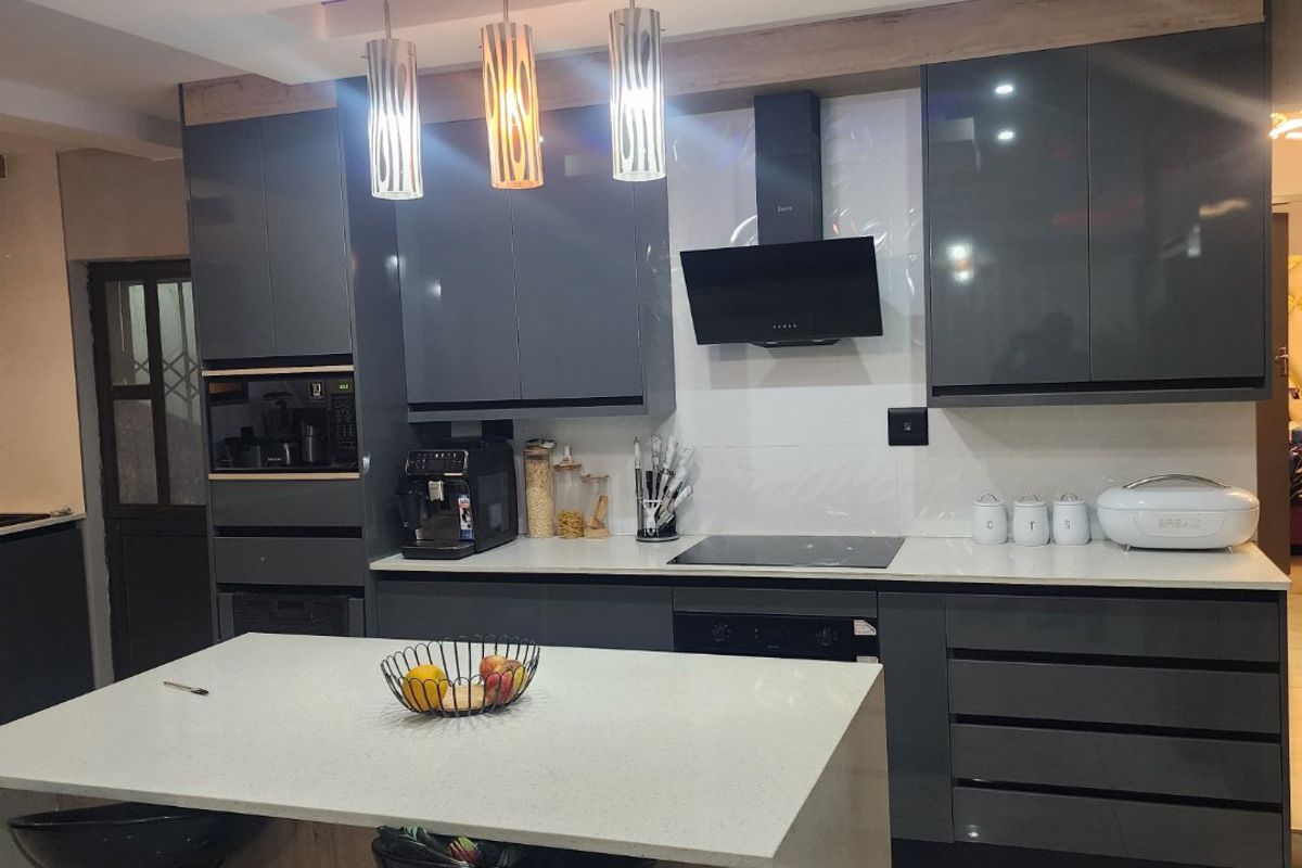 Modern kitchen featuring high-gloss cabinetry, a central island with quartz countertops, integrated appliances, and stylish recessed ceiling lighting with blue accent features.