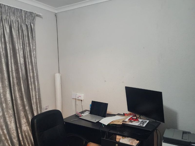 A functional home office space featuring neutral walls, coving, and window treatments, suitable for a dedicated workspace or study area.
