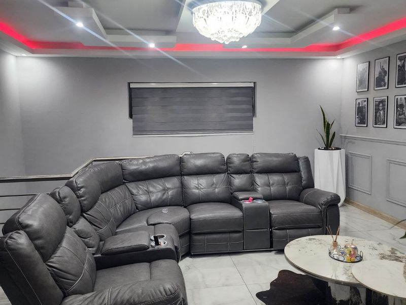 Modern living room featuring a recessed ceiling with integrated LED lighting, a crystal chandelier, and polished tiled flooring.