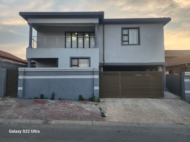A two-story residential property featuring a front balcony with stainless steel balustrades, a secure sliding gate, and a paved driveway.