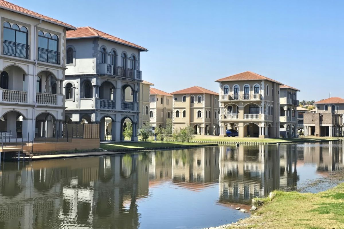 A scenic view of multi-story residential villas featuring canal frontage, private balconies, and classic architectural detailing along the water's edge.
