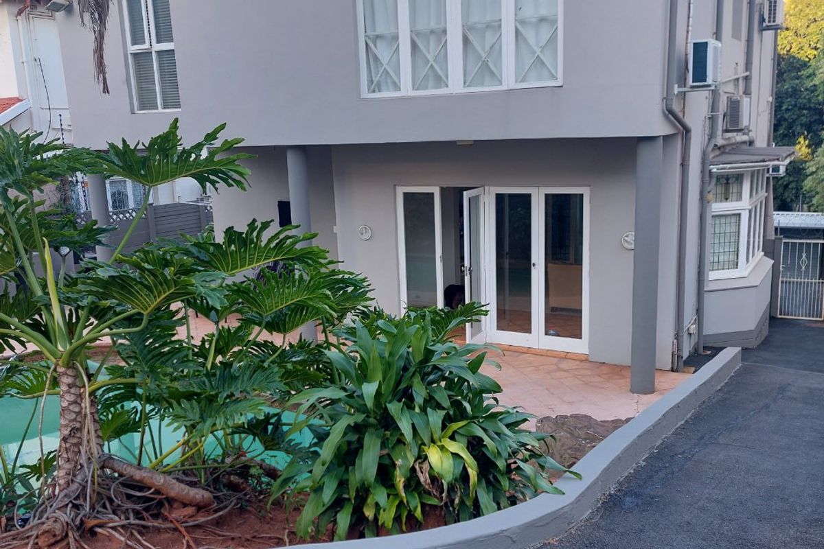 Rear view of a two-story house featuring a swimming pool, tiled patio area, and paved driveway access.