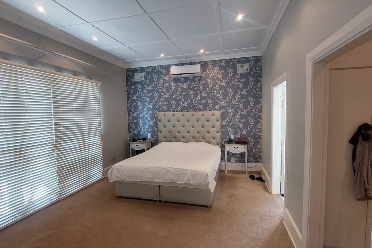 Spacious bedroom featuring a coffered ceiling, recessed lighting, split-system air conditioning, and large windows with venetian blinds.