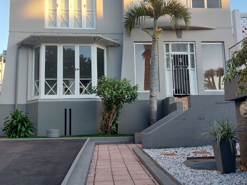 Front elevation of a two-story house featuring a paved walkway, asphalt driveway, and a secure entrance with a decorative security gate.