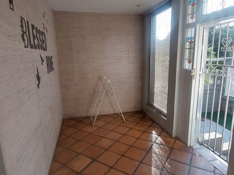 Entrance hall featuring terracotta floor tiles, textured wall finishes, and a secure entrance door with decorative stained glass panels.