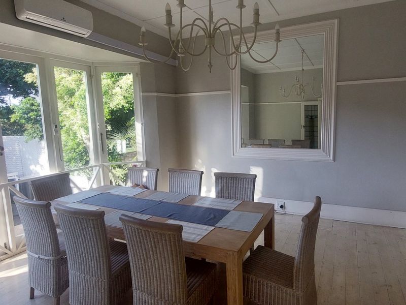 Bright dining room featuring timber flooring, a built-in wall mirror, picture rails, and direct access to the outdoors through classic french doors.