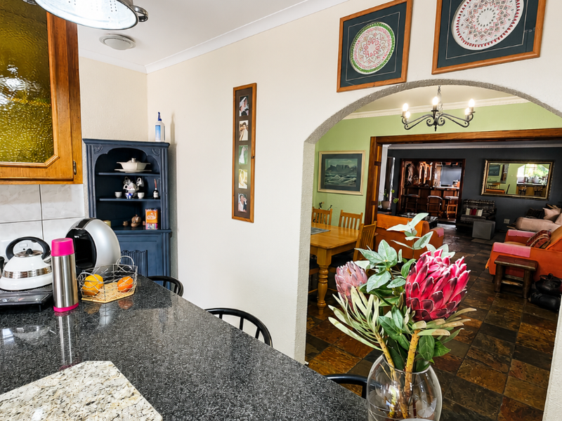 A kitchen featuring dark granite countertops and built-in cabinetry, with an arched opening leading into the adjacent dining and living areas.