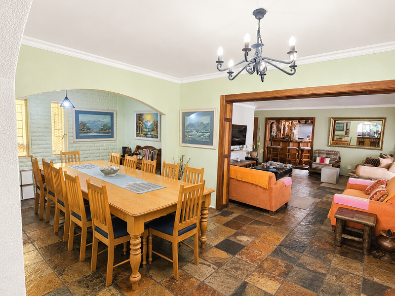 Spacious open-plan living and dining area featuring natural slate tile flooring, an arched entryway, and a built-in bar area.