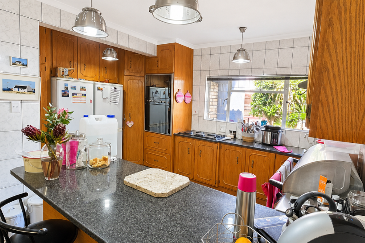 A functional kitchen featuring wooden cabinetry, granite countertops, a built-in oven, and a breakfast bar with pendant lighting.