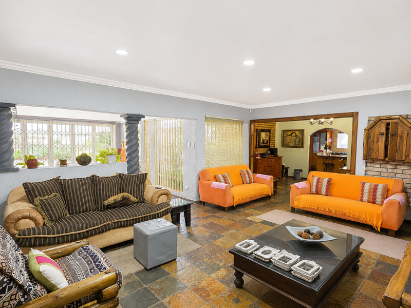 Spacious living area featuring natural slate tile flooring, recessed lighting, decorative columns, and a brick fireplace surround, offering a warm and inviting atmosphere.
