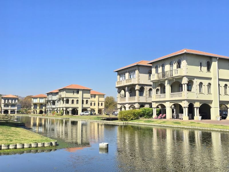 A scenic view of multi-story residential villas featuring classic architectural details, balconies, and arched ground-level patios overlooking a central canal.