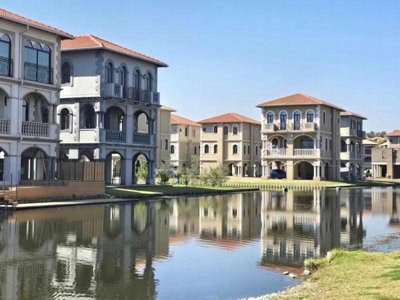 A scenic view of multi-story residential villas featuring canal frontage, private balconies, and classic architectural detailing along the water's edge.