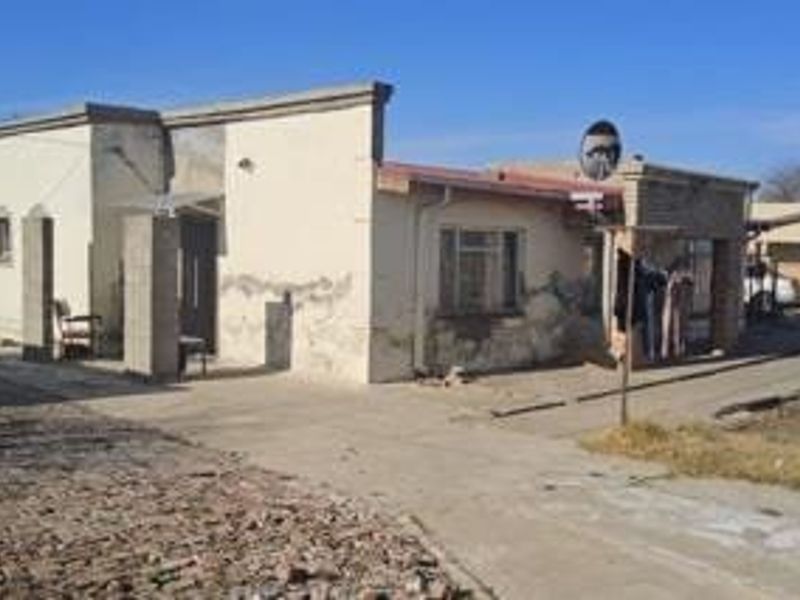 Front elevation of a single-story house featuring a concrete driveway and weathered exterior walls requiring maintenance and cosmetic updates.