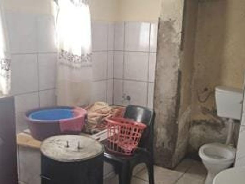 A small bathroom featuring a toilet and tiled wall finishes, currently requiring significant maintenance and cosmetic renovation to improve its overall condition.