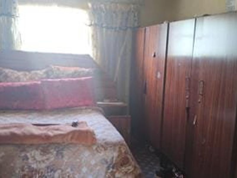 A bedroom featuring a built-in wooden wardrobe and natural light from the window.