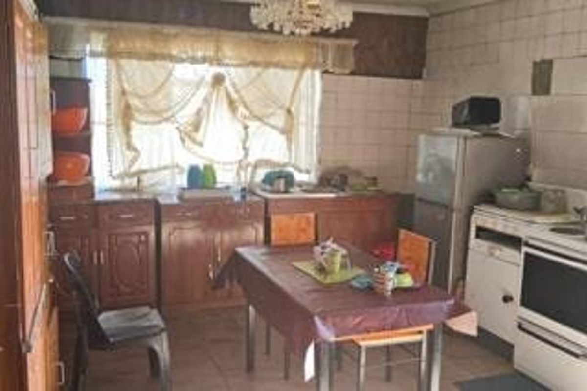 A dated kitchen featuring wooden cabinetry, tiled splashbacks, and a functional layout, offering significant potential for modern renovation and aesthetic updates.