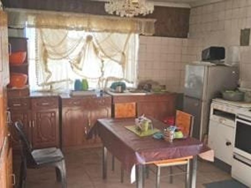 A dated kitchen featuring wooden cabinetry, tiled splashbacks, and a functional layout, offering significant potential for modern renovation and aesthetic updates.