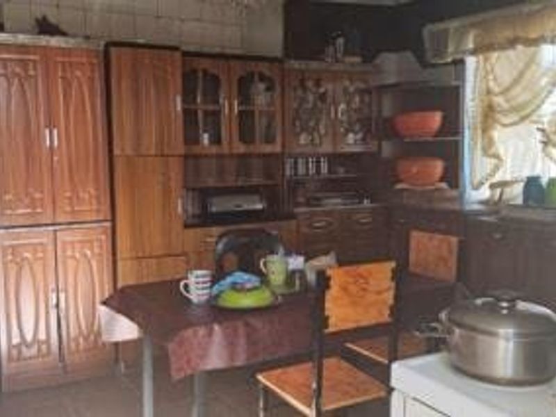 A dated kitchen featuring extensive built-in wooden cabinetry and tiled splashbacks, offering a traditional layout with significant potential for modern renovation.