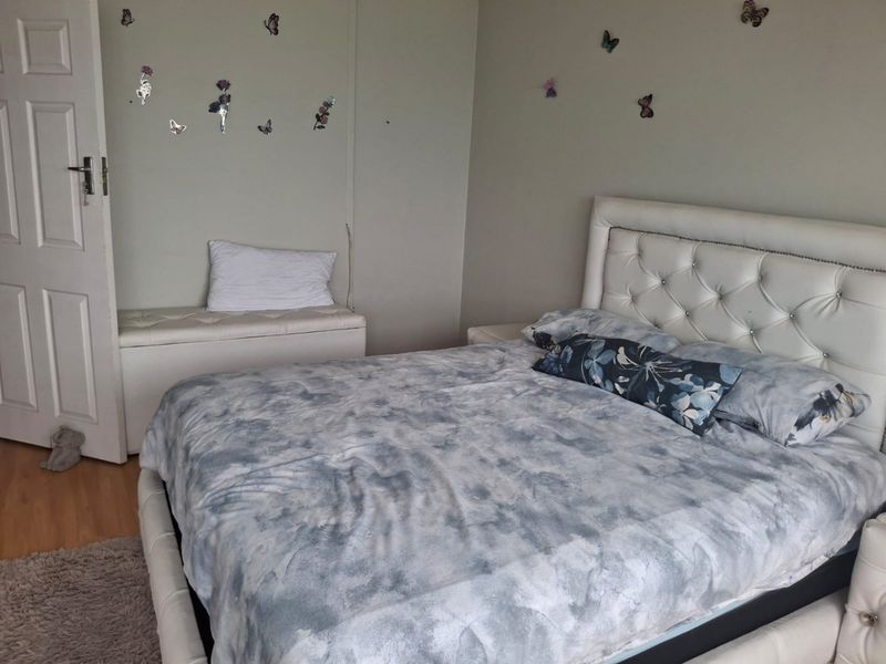 A bedroom featuring laminate flooring and a standard panel door, providing a functional and neutral living space.