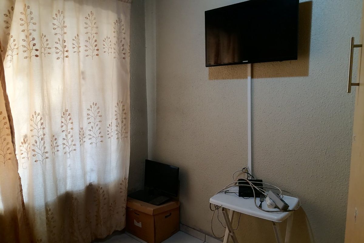 A small living area featuring tiled flooring and a wall-mounted television with visible cable management.