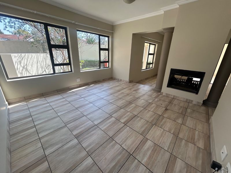 Spacious living area featuring wood-look tiled flooring, a built-in fireplace, and large windows that provide ample natural light.
