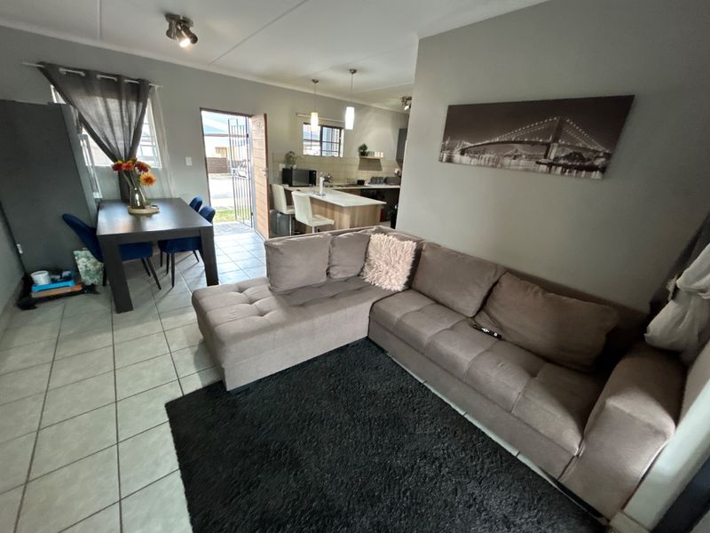 An open-plan living and dining area featuring tiled floors, a kitchen island, and direct access to the exterior entrance.