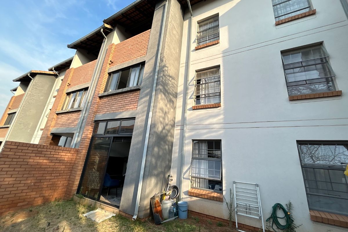 Rear elevation of a multi-story apartment building featuring a mix of brick and rendered finishes, sliding glass doors, and casement windows.
