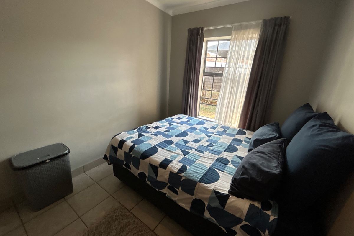 A functional bedroom featuring tiled flooring and a window with curtains, providing natural light and a neutral base for interior design.