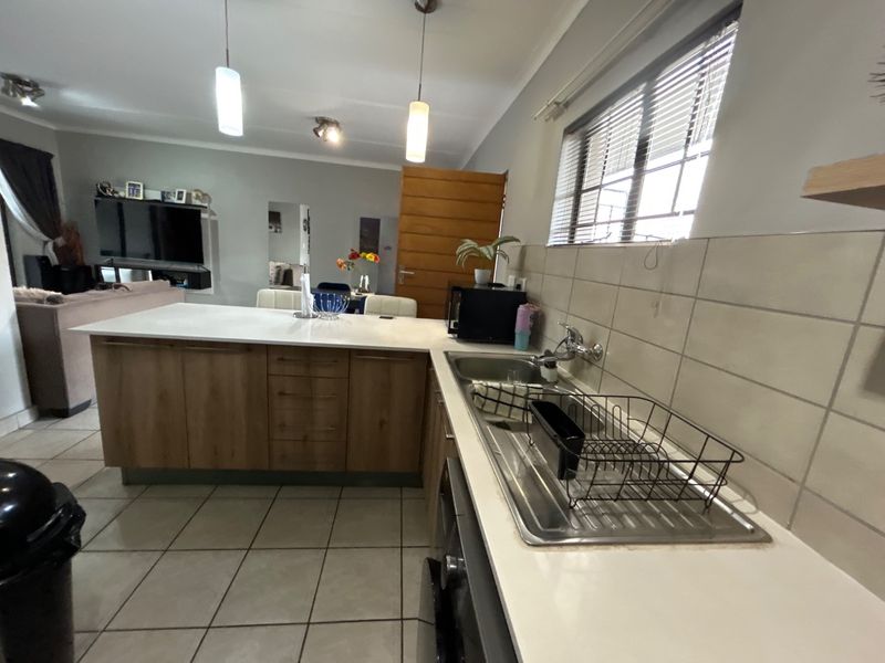Open-plan kitchen and living area featuring a central island, tiled flooring, and functional cabinetry, creating a versatile space for cooking and relaxation.