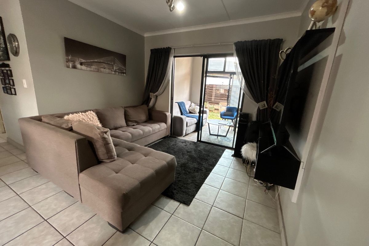 A living room featuring tiled flooring and a sliding glass door providing access to an outdoor patio area.