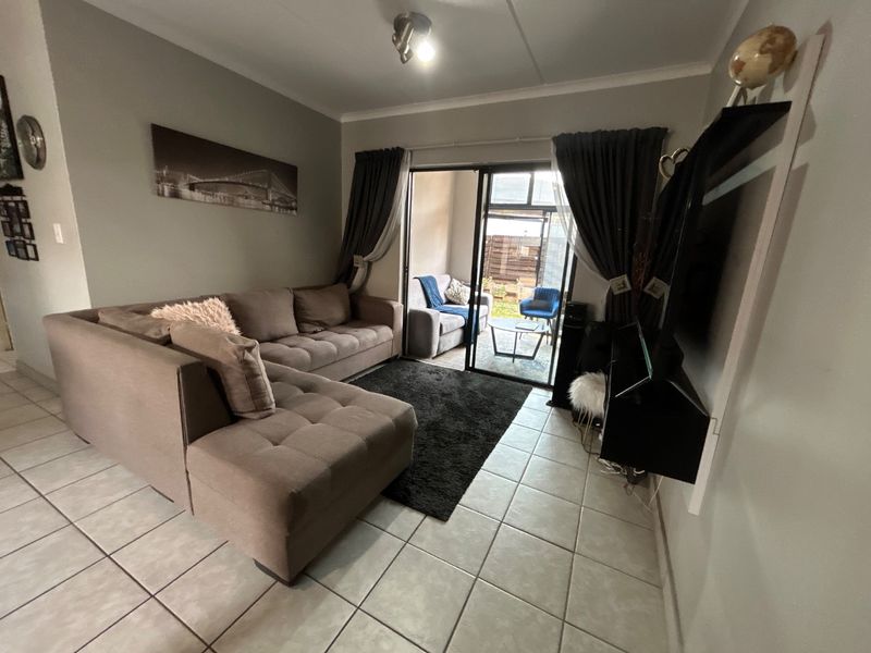 A living room featuring tiled flooring and a sliding glass door providing access to an outdoor patio area.