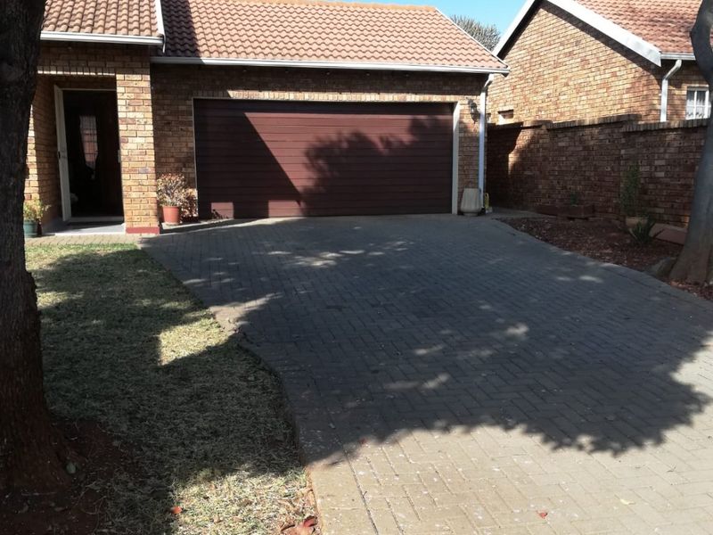 Front exterior view of a face brick townhouse featuring a paved driveway, single garage, and tiled roof.