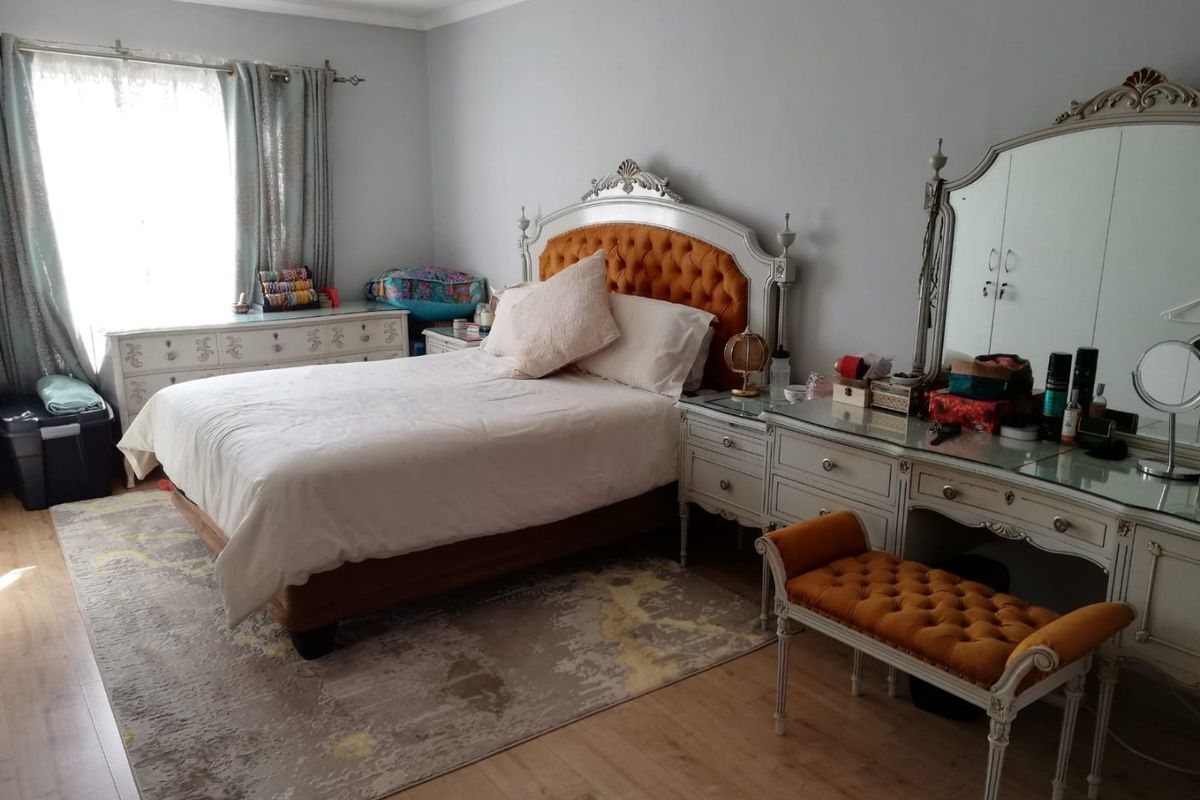 A spacious bedroom featuring light-toned laminate flooring, recessed downlighting, and decorative coved cornicing, providing a neutral foundation for personal styling.