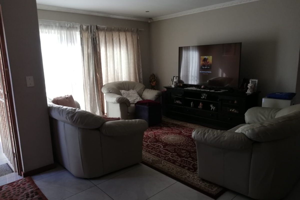 A living room featuring tiled flooring, recessed downlighting, and decorative ceiling cornicing, providing a functional space for relaxation.