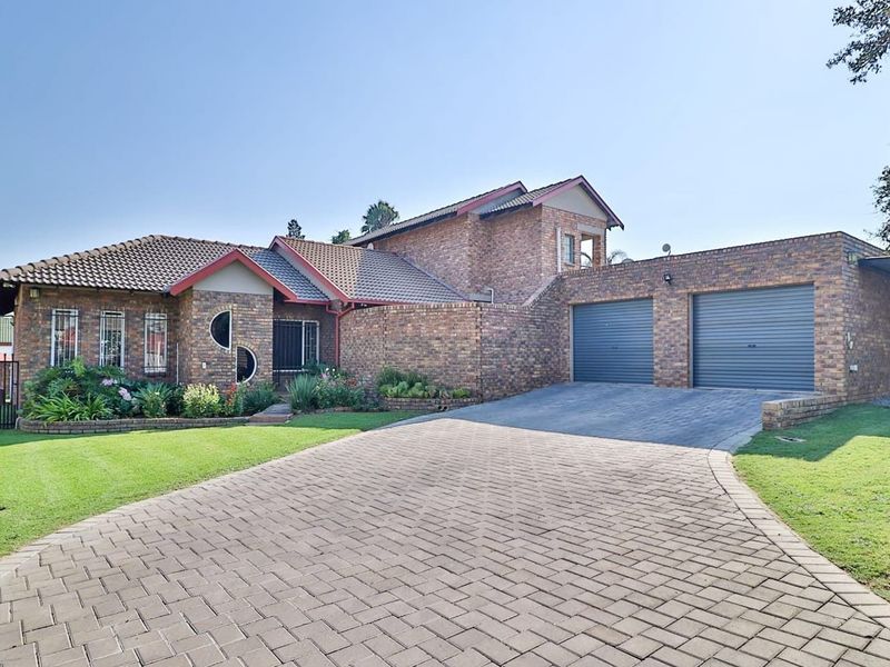 A well-maintained face brick family home featuring a double garage, paved driveway, and established front garden.