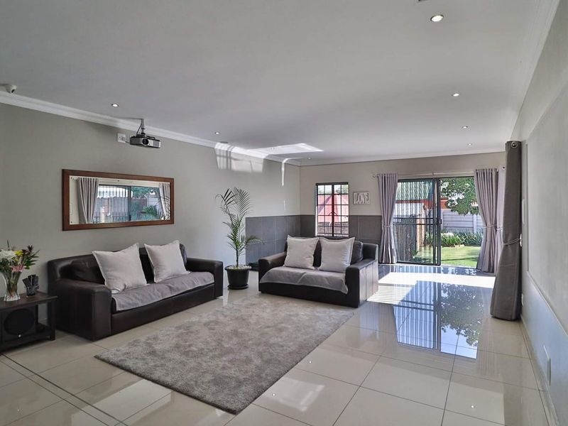 Spacious living room featuring polished tiled flooring, recessed downlighting, and direct access to the rear garden through a sliding glass door.