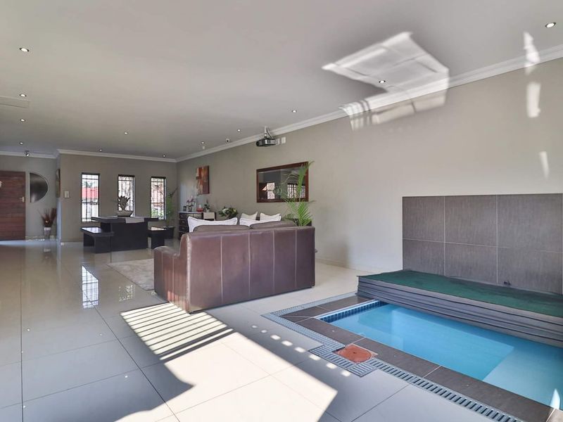 Spacious open-plan living area featuring a unique integrated indoor swimming pool, polished tiled flooring, and modern recessed lighting.
