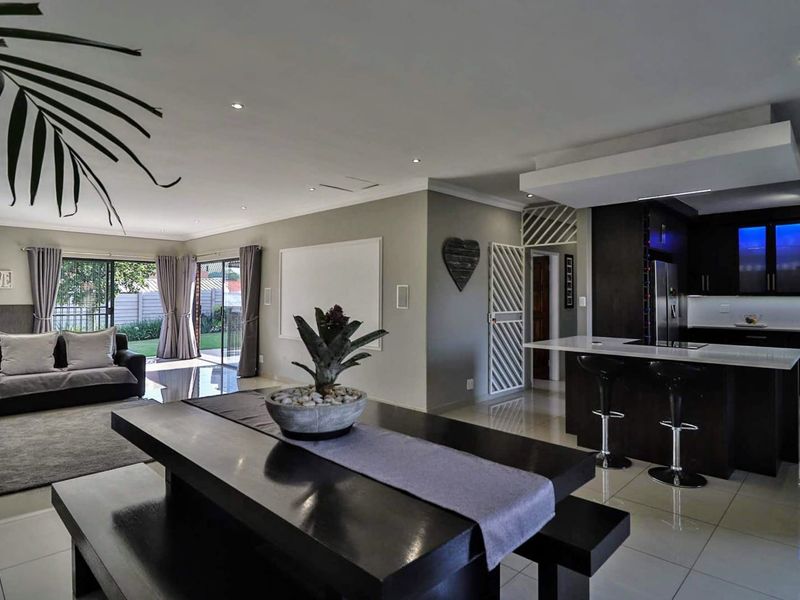 Spacious open-plan living area featuring modern porcelain tiles, recessed lighting, and a contemporary kitchen with a central island and sleek cabinetry.