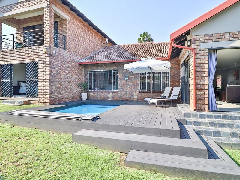 A well-maintained rear exterior featuring a swimming pool, modern composite decking, and direct access to the home through sliding doors.