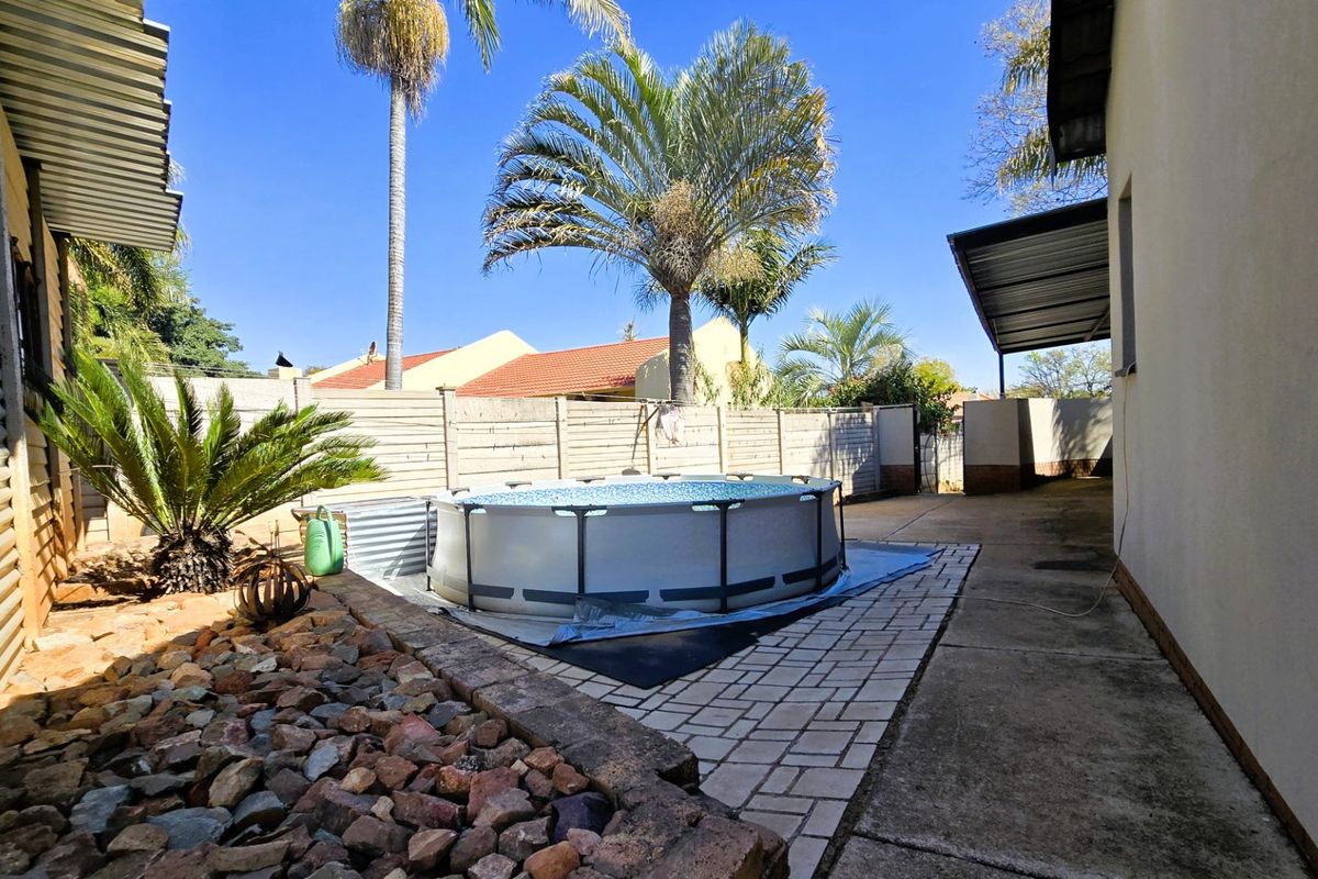 Rear outdoor area featuring an above-ground pool, paved patio space, and perimeter fencing, providing a functional backyard setting.