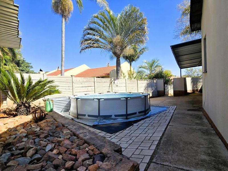 Rear outdoor area featuring an above-ground pool, paved patio space, and perimeter fencing, providing a functional backyard setting.
