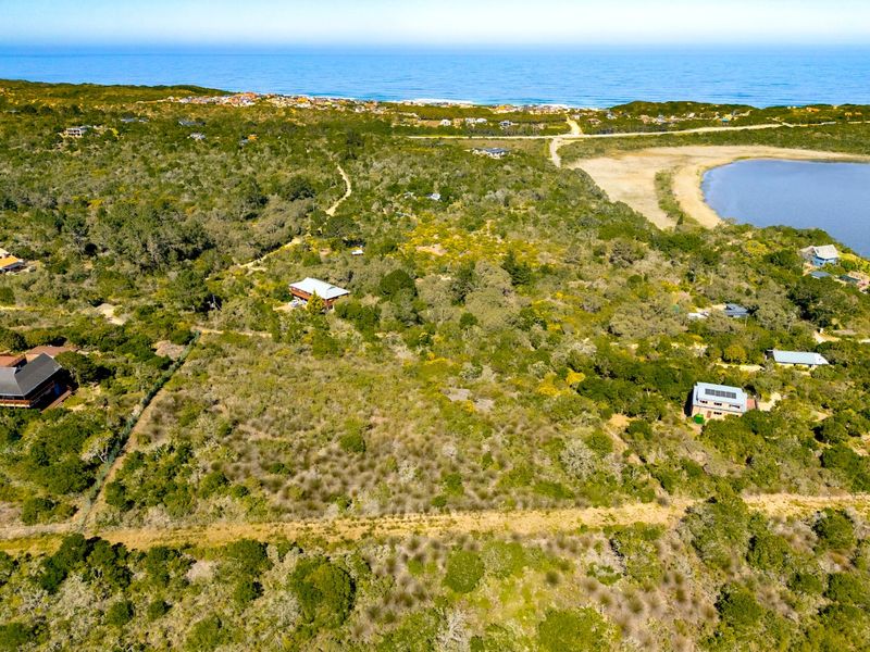 Aerial view of a large, undeveloped residential plot surrounded by natural coastal vegetation, with proximity to the ocean and a nearby lagoon.