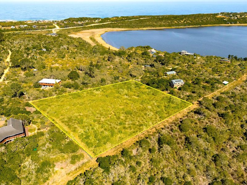 Aerial view of a vacant residential plot surrounded by coastal vegetation, featuring proximity to the lake and ocean.