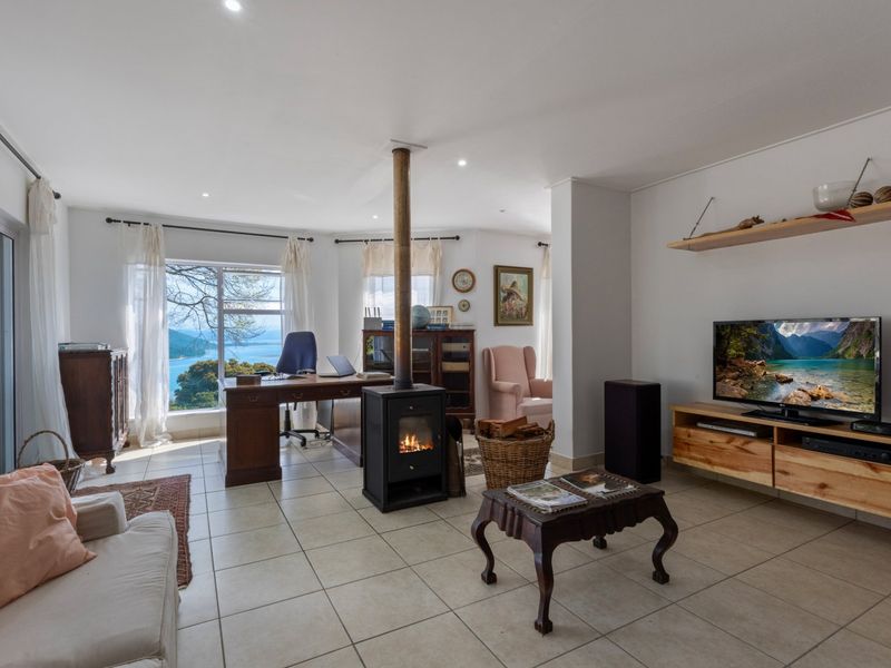Spacious living area featuring a central freestanding fireplace, tiled flooring, and large windows offering scenic water views.